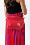 A women holding the bright pink bag with a brown body strap and the meanwhile logo.
