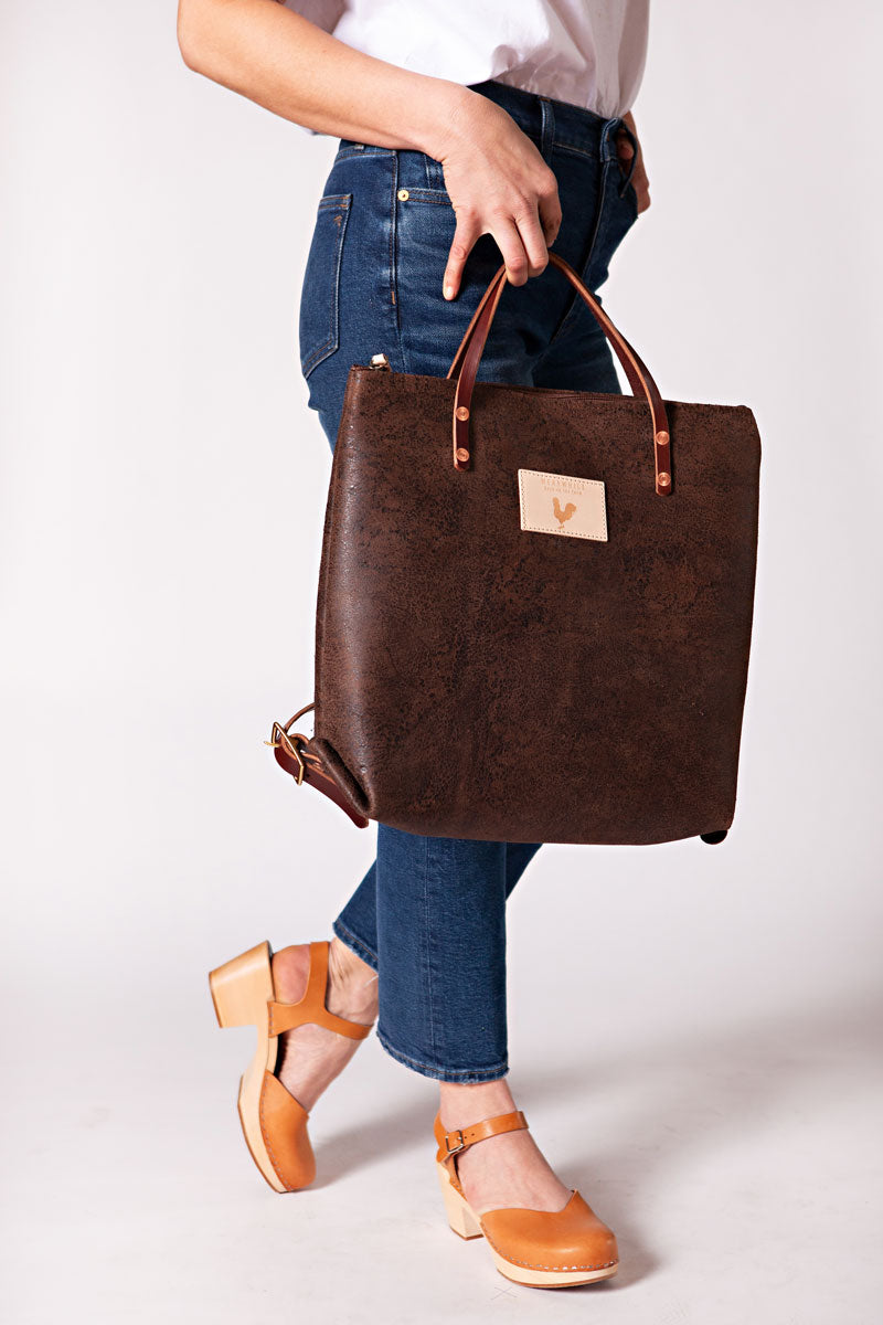 Woman wearing the birch mocha backpack with meanwhile logo and dark brown straps.
