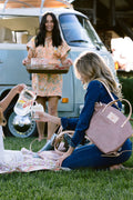 Young women having a picnic with pink leather bag