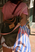 Person carrying a green backpack with the Meanwhile Back on the Farm logo