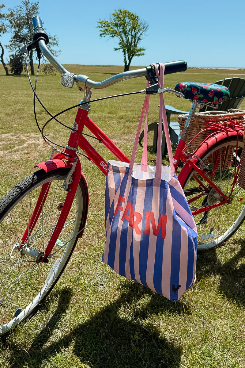 Pink and blue striped tote with 'FARM' lettering and a tiny rooster detail in the bottom corner