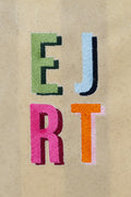 A close up view of the Natural XL Canvas Snap Tote with Embroidered letters 'E', 'J', 'R', and 'T' in different colors