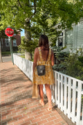 Woman walking on a sidewalk wearing a black leather saddle bag