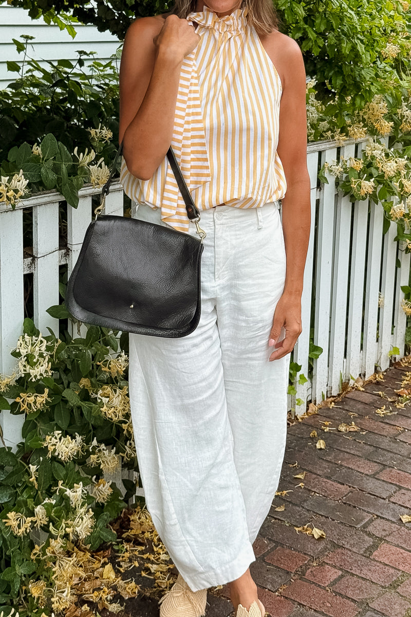Woman holding a black leather saddle bag  with brass hardware