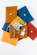 All different color Meanwhile Back on the Farm wallets with items like money and jewelry