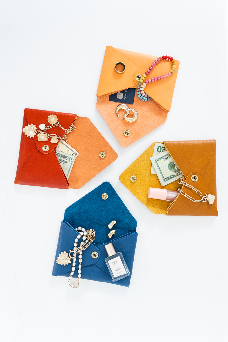 Four different color Meanwhile Back on the Farm wallets with items like money and jewelry