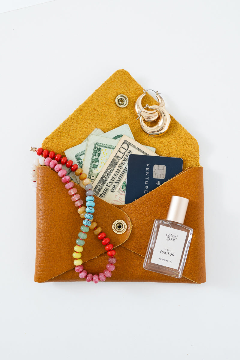 Brown leather Meanwhile Back on the Farm wallet with a colorful beaded necklace, earrings, money, and card