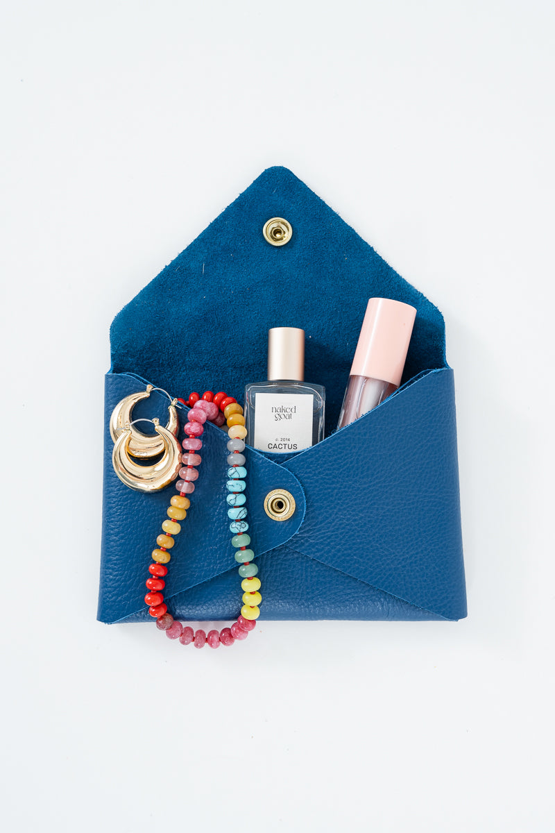 Blue leather Meanwhile Back on the Farm wallet with a colorful beaded necklace, earrings, and lip gloss