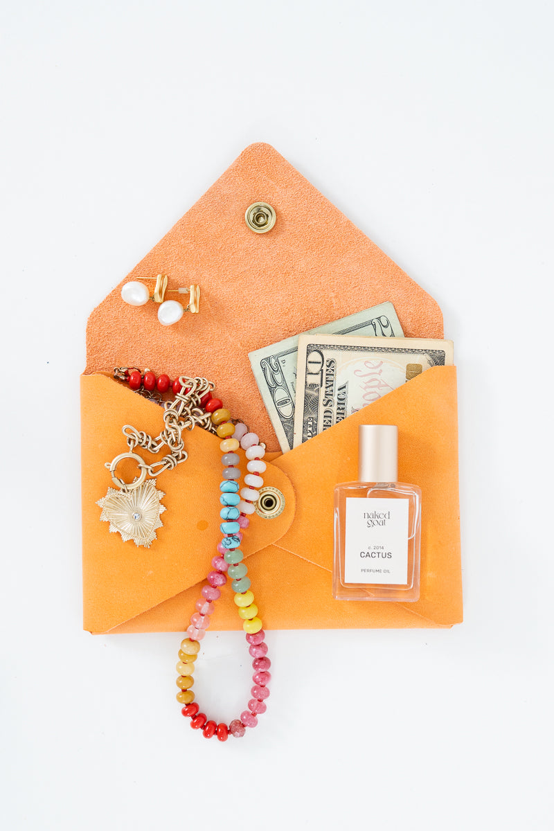 Orange leather Meanwhile Back on the Farm wallet with a colorful beaded necklace, earrings, and money