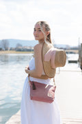 Woman wearing a pink leather bag by a body of water.