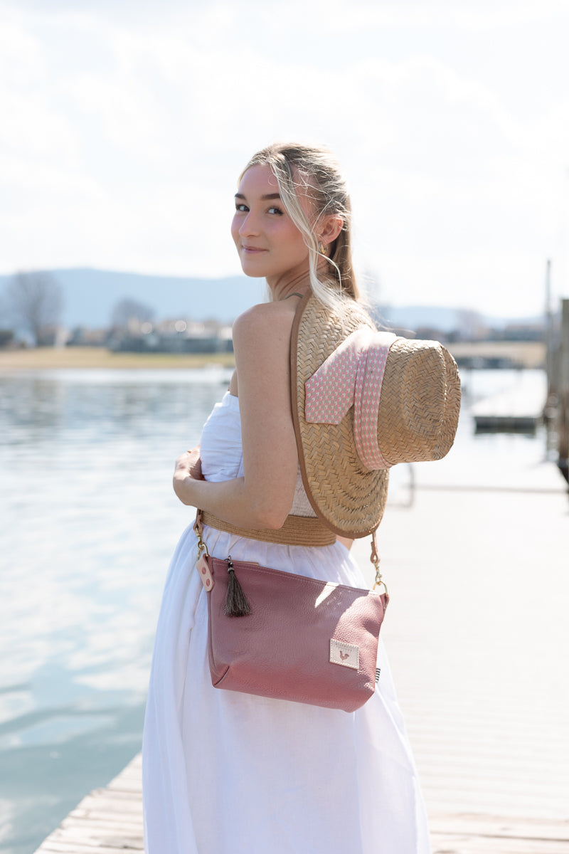 Woman wearing a pink leather bag by a body of water.