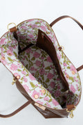An overhead view of a brown leather handbag showing its floral-patterned interior lining with pink flowers and green leaves on a white background.