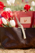 Red and brown bag with flowers in the bag on a blurred floral background
