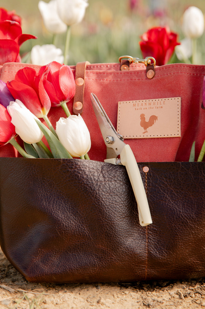 Red and brown bag with flowers in the bag on a blurred floral background