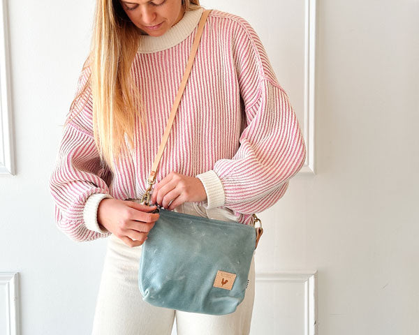 Girl holding a Dusty Blue Leather Sling Bag with tan straps