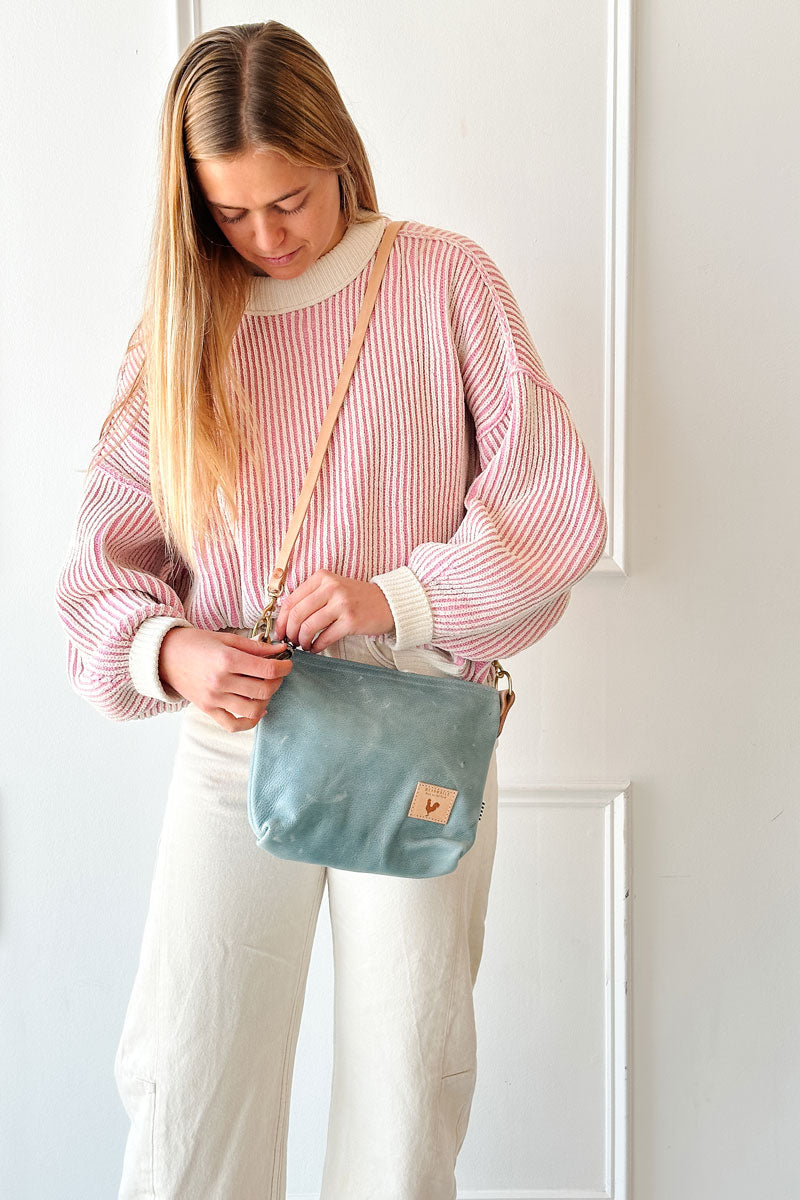 Girl holding a Dusty Blue Leather Sling Bag with tan straps