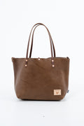 A chestnut brown tote bag with a visible brand logo on a white background. Handmade by Meanwhile Back on the Farm in Lynchburg,VA