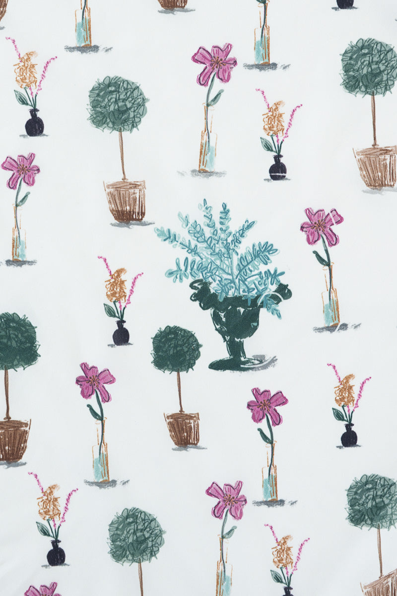 A repeating botanical pattern on a white background featuring potted topiary trees, pink flowers, and a central teal leafy arrangement in a dark urn. Proudly handcrafted by Meanwhile Back on the Farm in Lynchburg, Va.