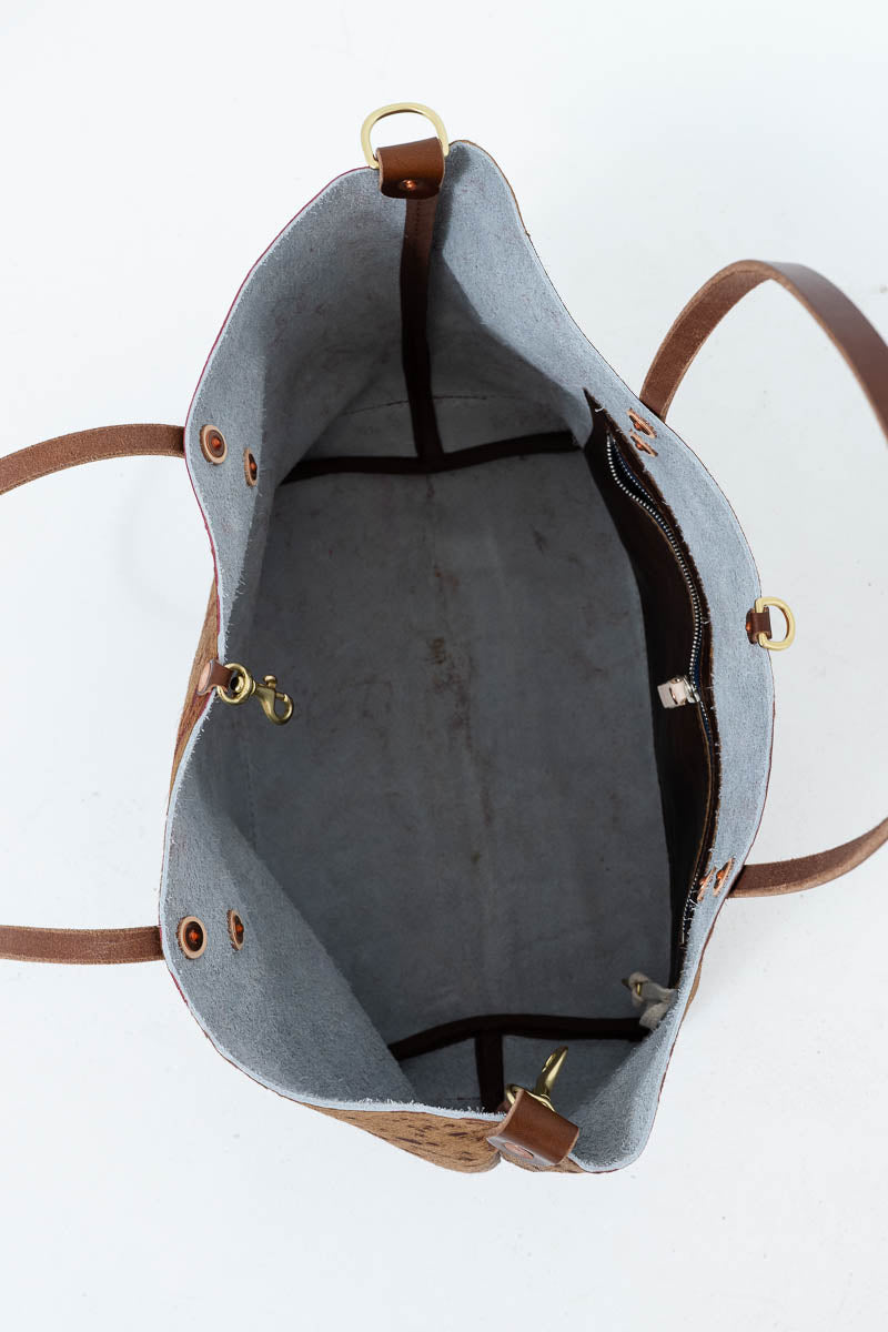 Top-down view of a tote bag interior with a light gray felt lining, brown leather trim, and gold-tone hardware on a white background. Handcrafted by Meanwhile Back on the Farm in Lynchburg, Va.