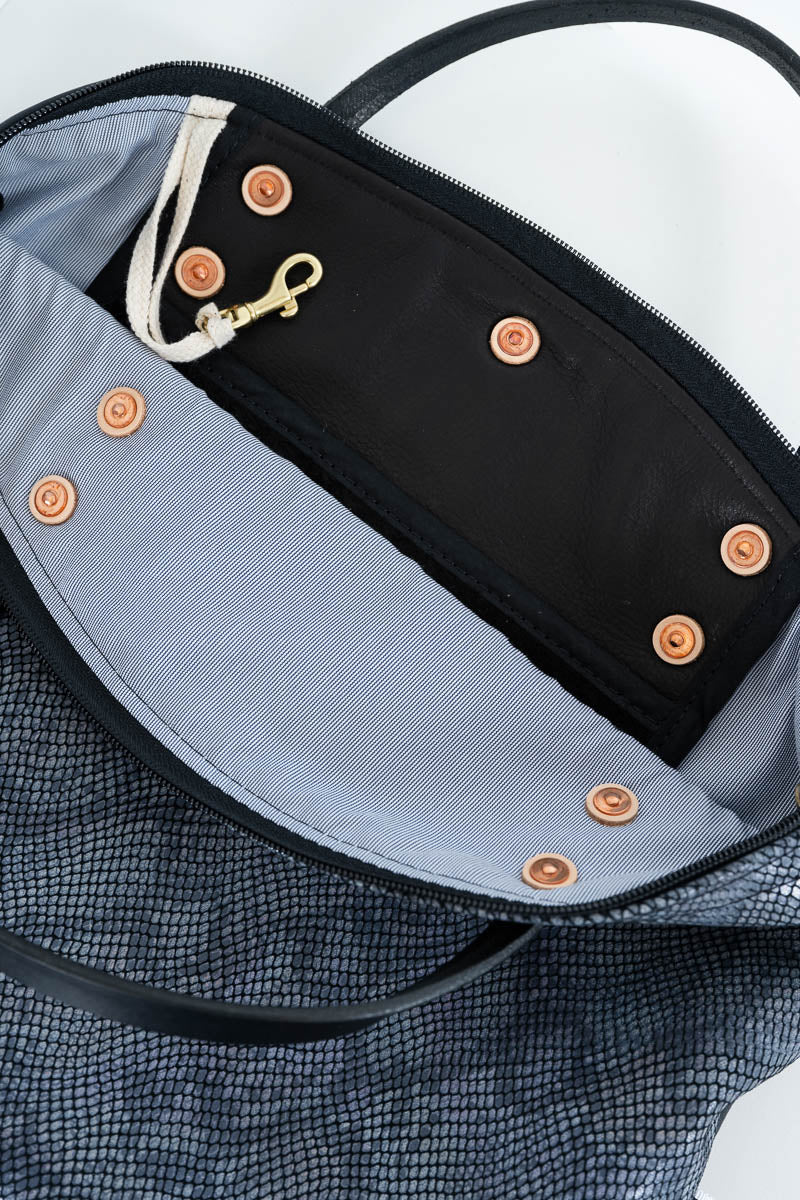 Close-up of the interior of a textured dark gray tote bag, showing a black zippered compartment with a light gray lining, copper-toned snap buttons, a white drawstring, and a gold-tone clip. Handcrafted by Meanwhile Back on the Farm in Lynchburg, Va.