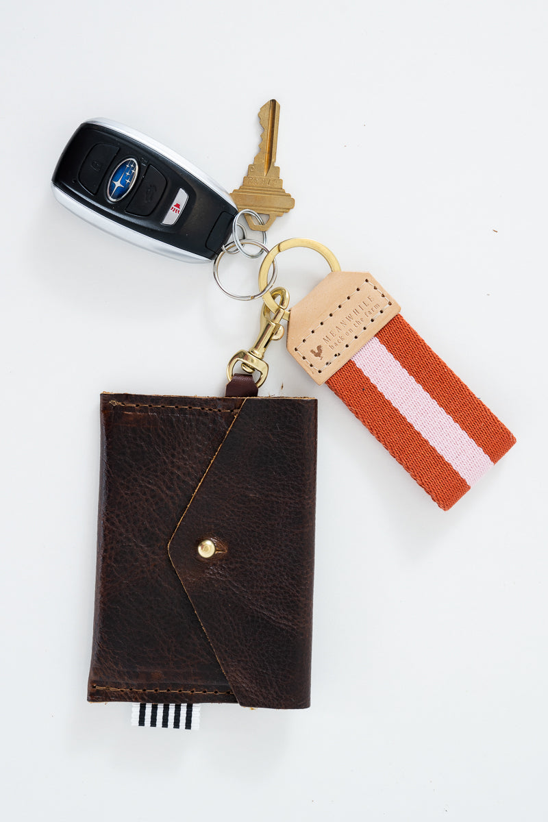Two orange and pink striped Meanwhile Back on the Farm webbing key fobs