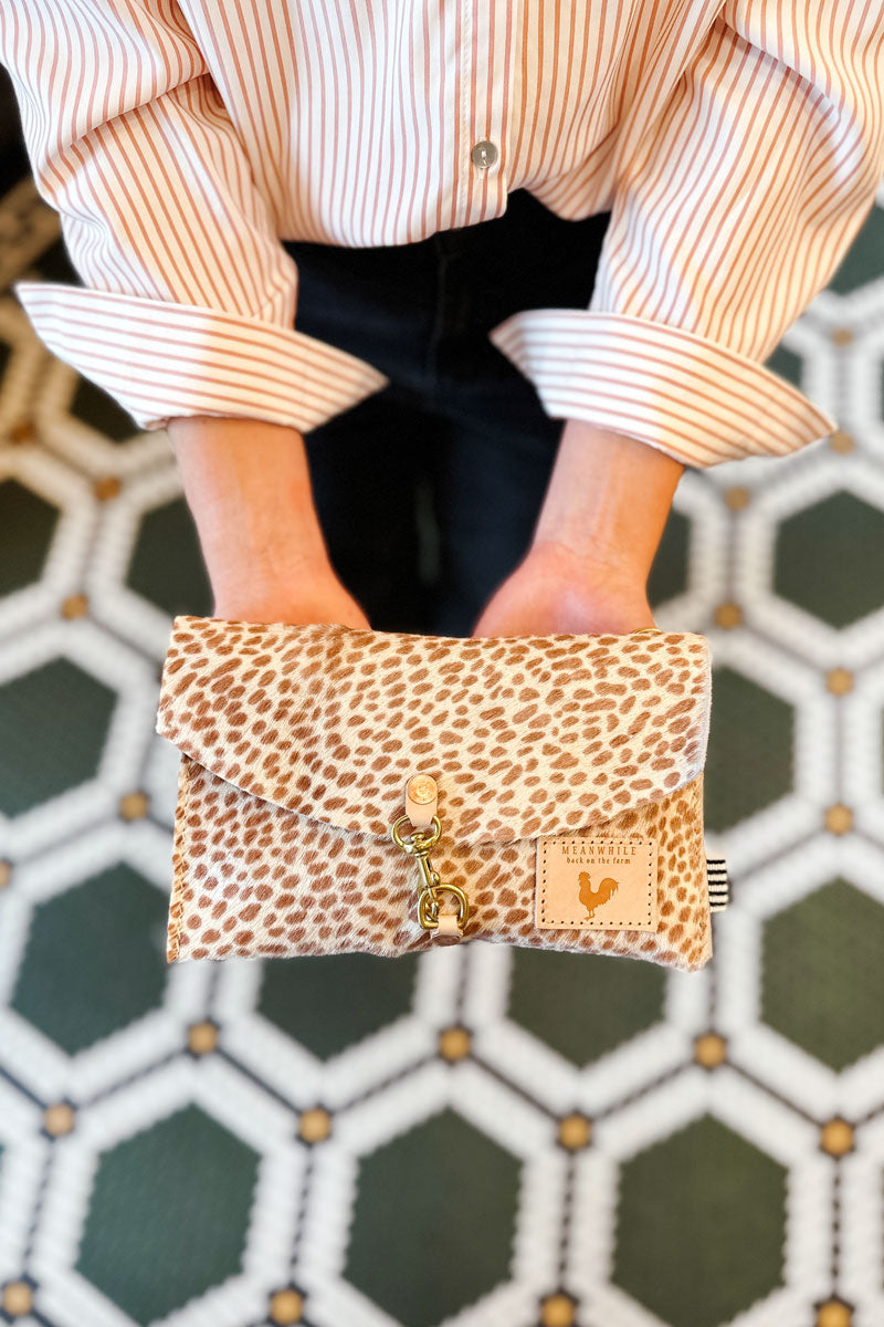 Hands holding a small leopard hair on hide leather envelope clutch