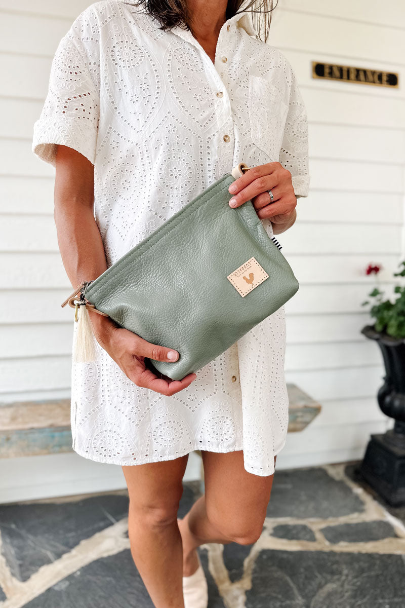 Model holding sea foam green medium sized leather bag with cream colored shoulder straps