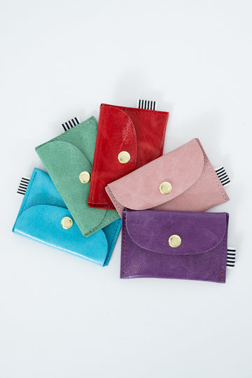 Blue, green, red, pink, and purple leather snap pouches with gold snap closures
