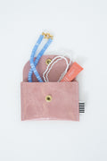 Pink snap pouch with necklaces and a lip balm
