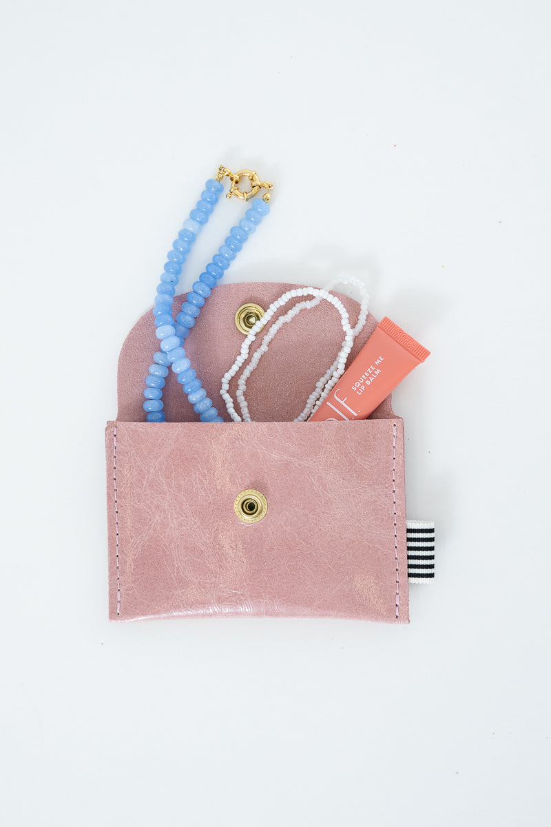 Pink snap pouch with necklaces and a lip balm