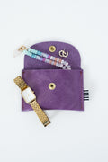 Purple snap pouch with gold watch, earrings, and jewelry