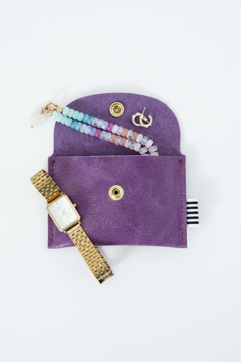 Purple snap pouch with gold watch, earrings, and jewelry