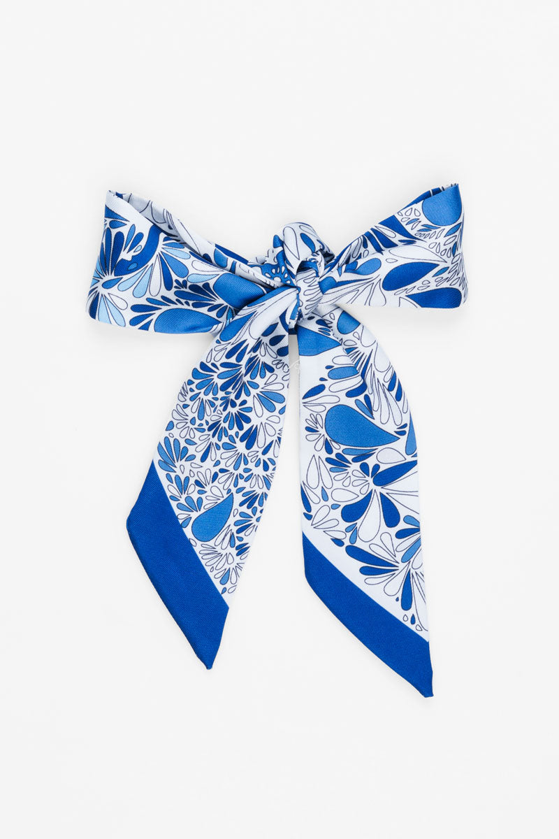 Picture of white scarf with blue paisley print tied into a bow