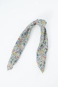 A knotted scarf featuring a dense, small-scale multicolor floral print on a white base, displayed against a clean white background. Handmade by Meanwhile Back on the Farm in Lynchburg,VA