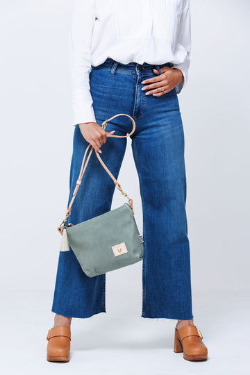 Model holding sea foam green medium sized leather bag with cream colored shoulder straps