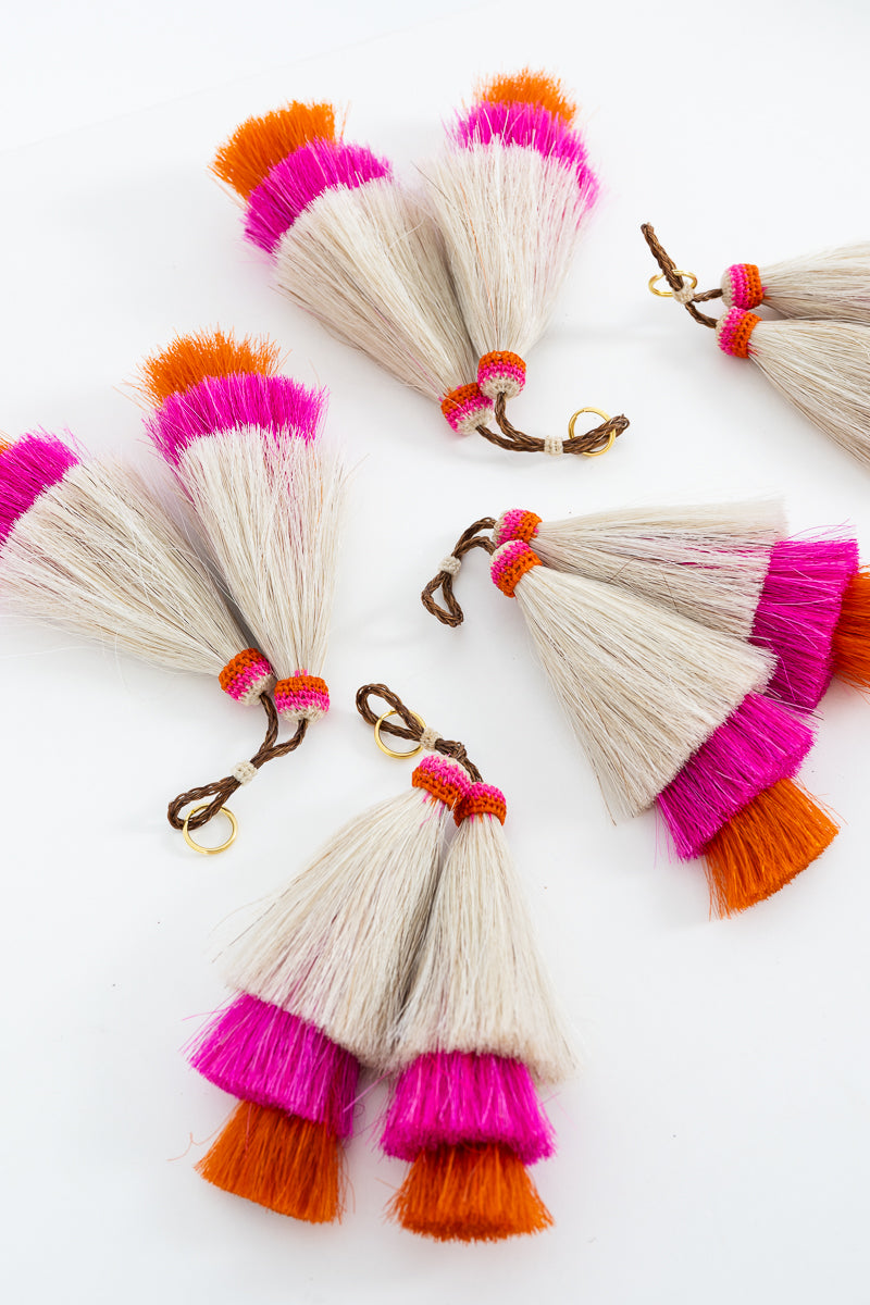 Four pairs of tassels in cream with vibrant pink and orange tips, displayed on a clean white background. Handmade by Meanwhile Back on the Farm in Lynchburg,VA
