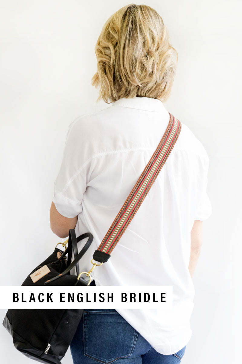 Girl wearing the Cranberry Italian Webbing Crossbody Strap with a small Black leather bag with the text "Black English Bridle"