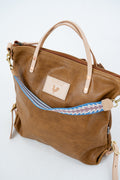 Brown leather Meanwhile Back on the Farm bag with a blue and white webbing strap