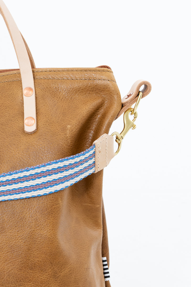 Brown leather Meanwhile Back on the Farm bag with a blue and white webbing strap
