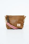 Brown leather bag with the Meanwhile Back on the Farm logo and a pink webbing strap