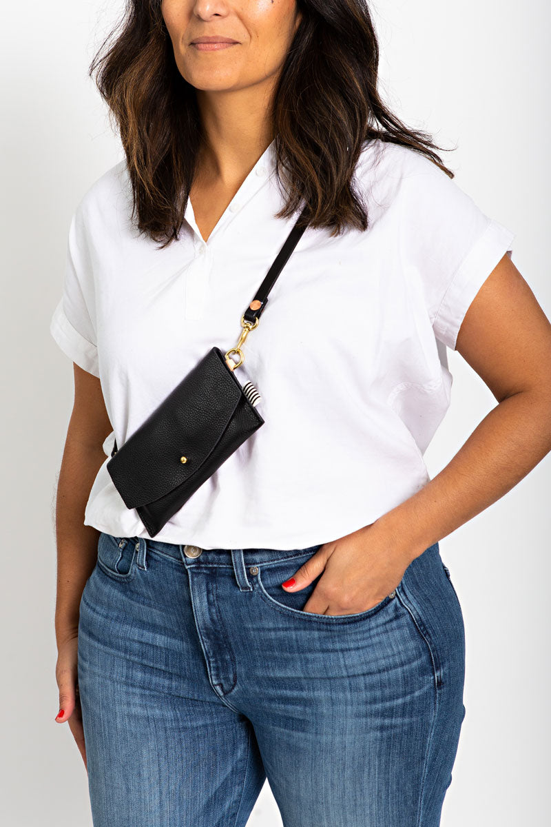 A woman wearing the black belt bag with a black belt strap and meanwhile logo.