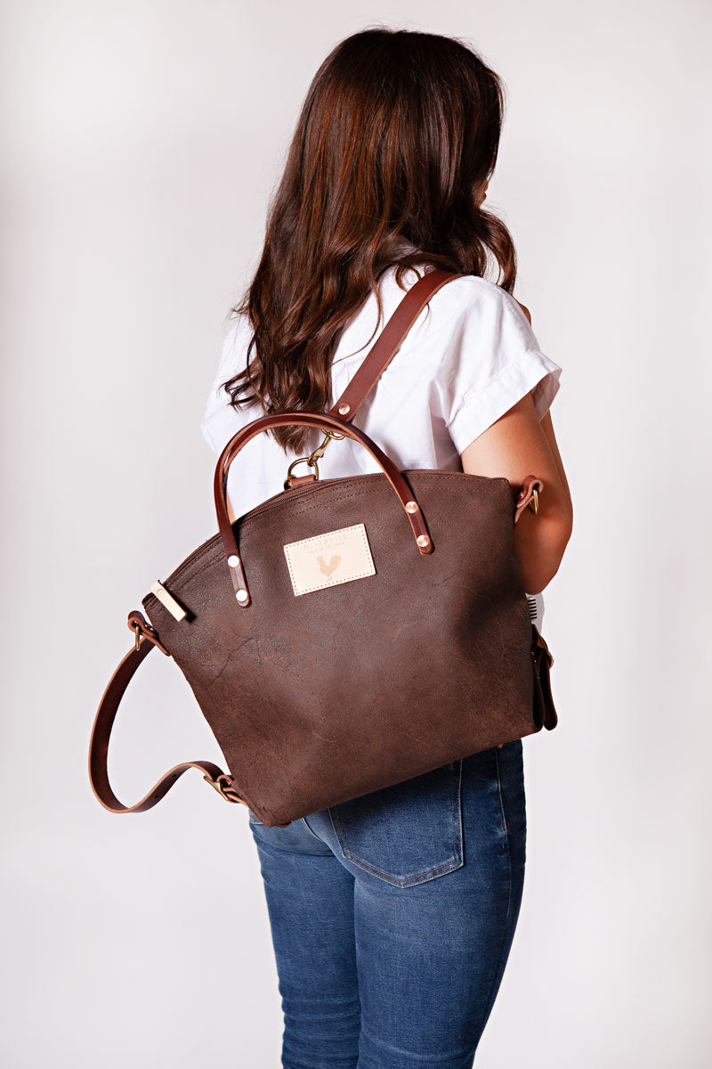 Woman wearing the mocha backpack with meanwhile logo and dark brown straps.