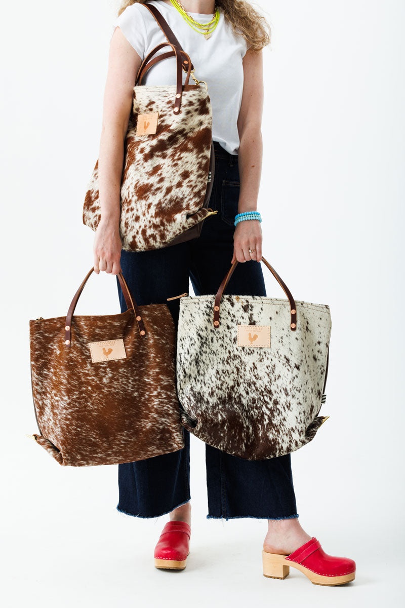 Model wearing brushed brown cowhide backpack style bag with brown leather straps.