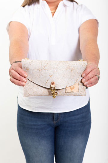 A woman holding the birch white bag with meanwhile logo and a hook clasp to close the bag.
