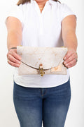 A woman holding the birch white bag with meanwhile logo and a hook clasp to close the bag.