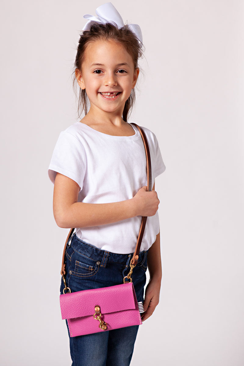 Mom and her daughter looking at each other both wearing matching pink fold over clutches.