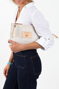 Woman holding birch white clutch with meanwhile logo and white tassel zipper.